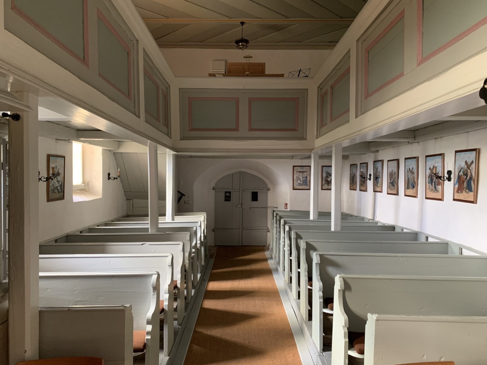 In der Kirche: Blick von der Kanzel auf den Ausgang. Rechts und links Sitzbänke.