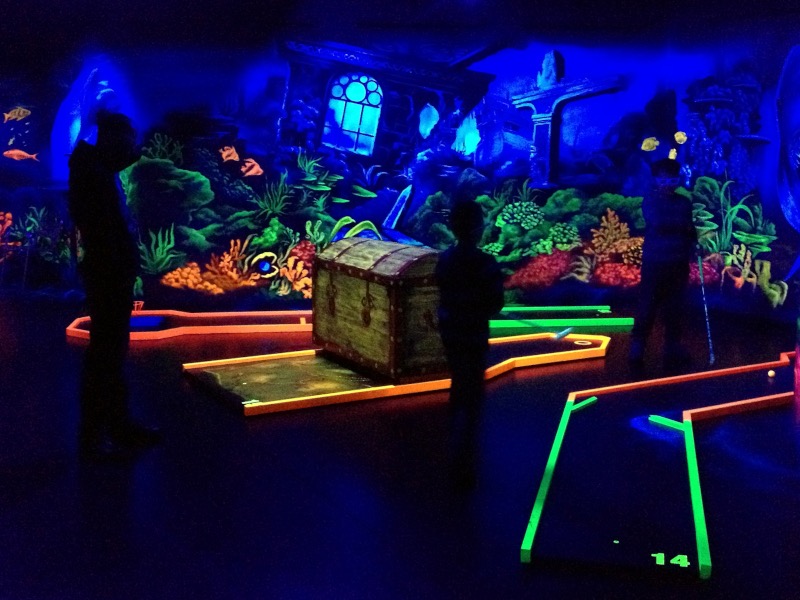 Neon-leuchtende Truhe zwischen Minigolfbahnen im Unterwasser-Thema