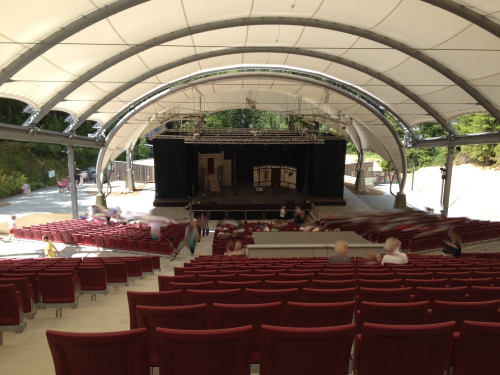 Zwischen rundem weißen Zeltdach und roten Sitzplätzen ist in der Mitte die Bühne zu sehen.