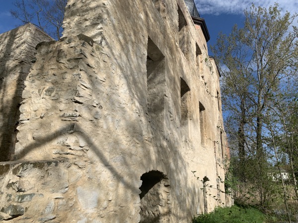 Außenwand der Ruine vom Wasserschloss in Geilsdorf neben zwei Bäumen