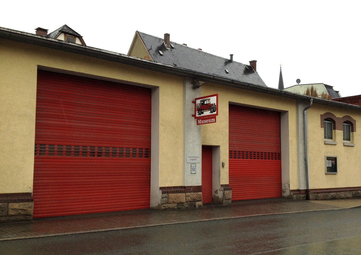 Zwei rote Garagentore einer Garage mit beiger Hausfassade