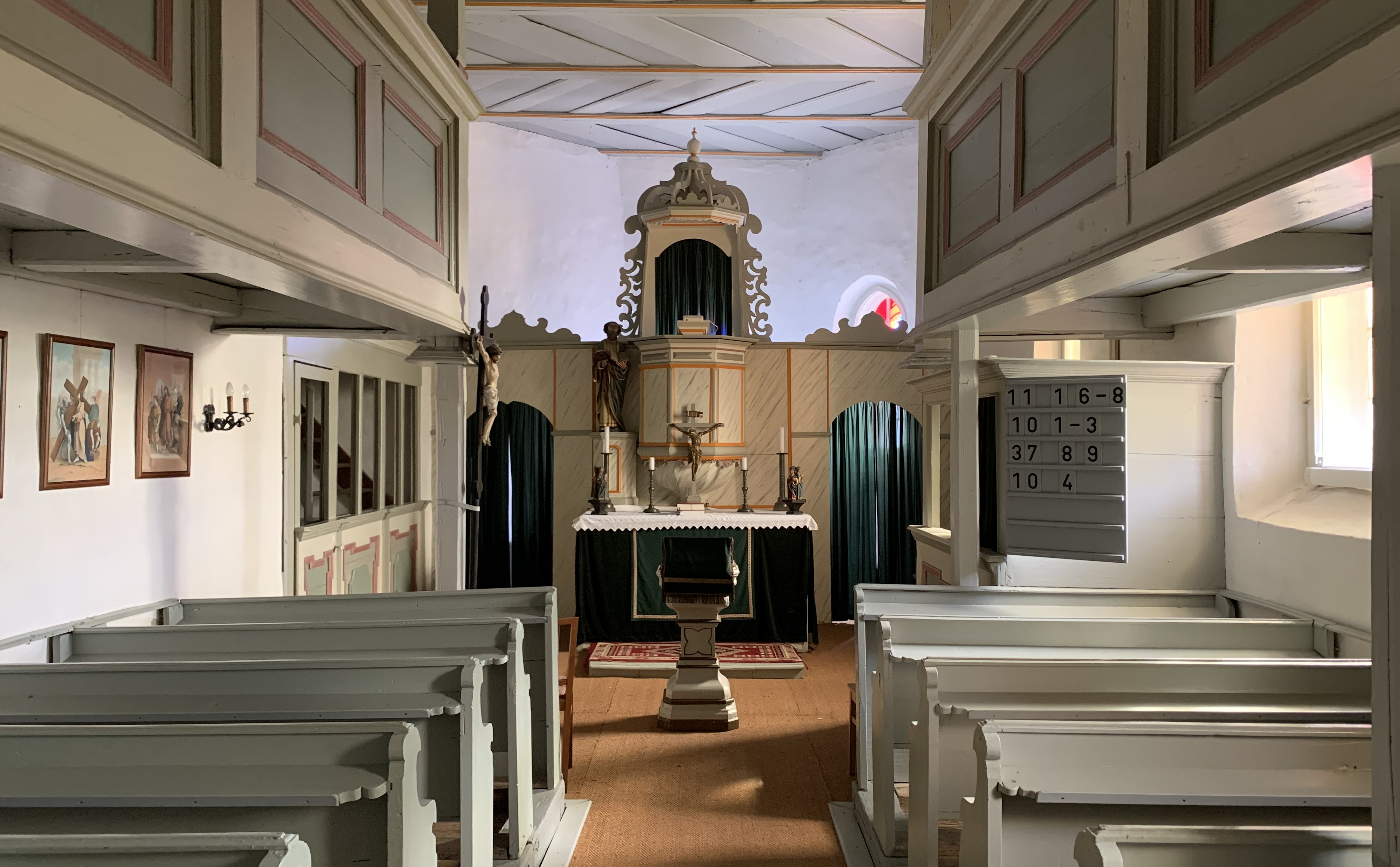 Innenansicht der Kapelle mit Blick auf Altar. In der Mitte Gang zwischen den Bnken.