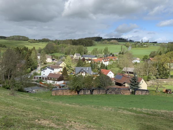 Eine Siedlung im Tal unter leicht bewlktem blauebn Himmel.