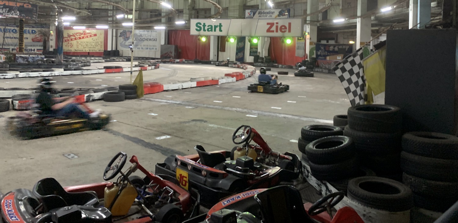 Kartbahn in Karthalle im Start-Ziel-Bereich. Im Vordergrund Karts und Reifenstapel