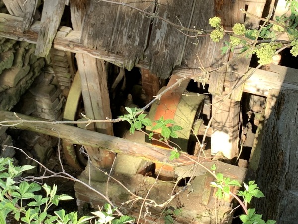 Rad mit Riemen angetrieben in Steinumbau unter Holzdach. Sicht von schrg oben.