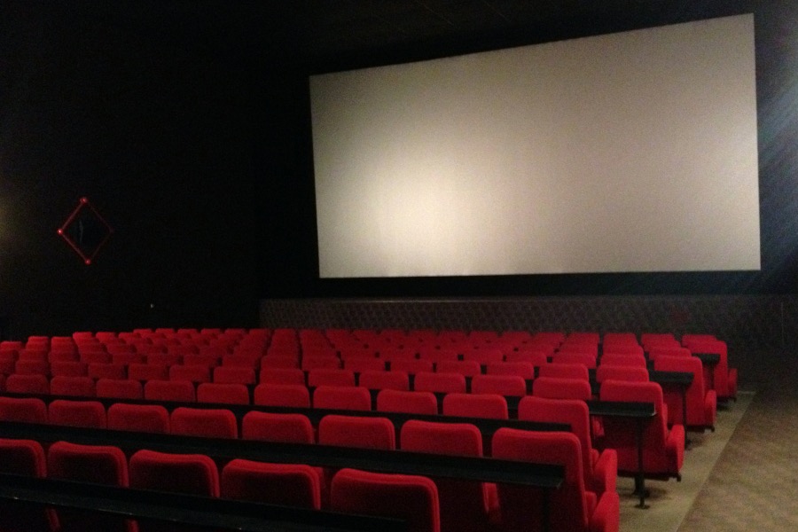 Rote gepolsterte Kinositze in Reihe im Kinosaal mit Blick auf die Leinwand