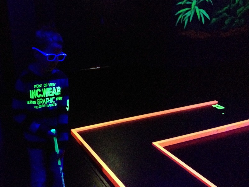 Minigolfspieler mit 3D-Brille neben oranger Bahn