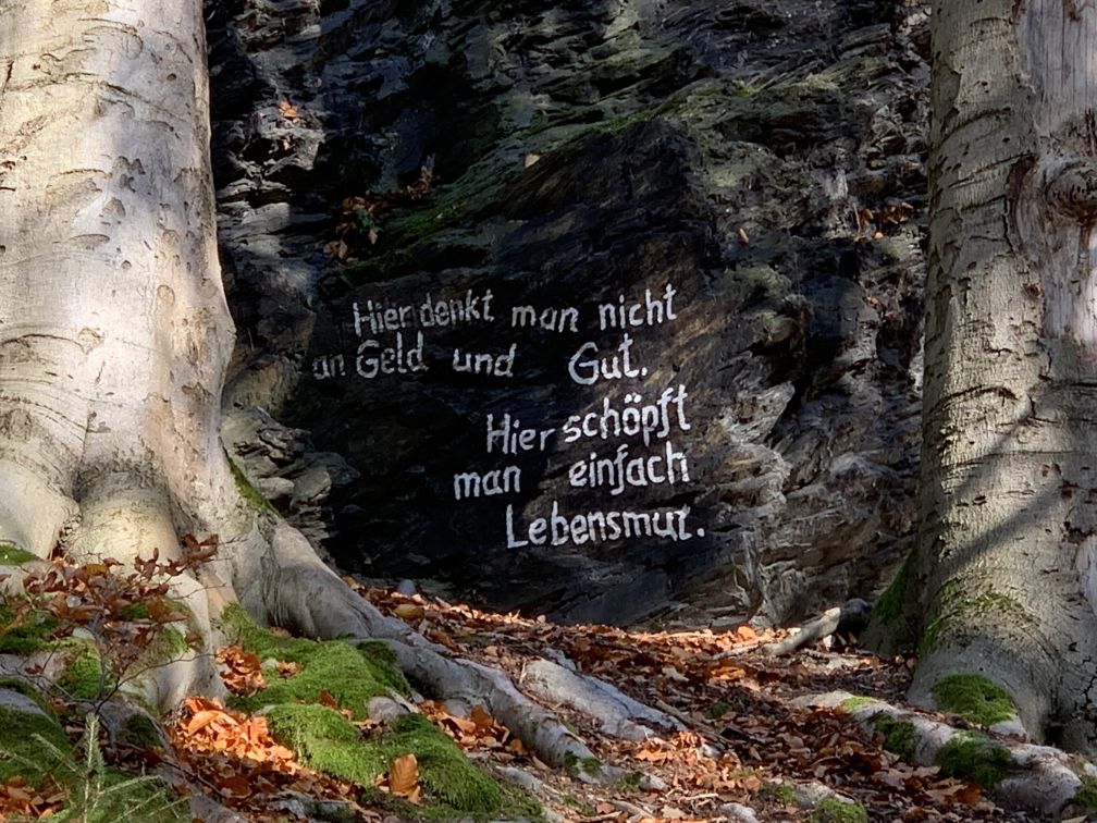 Felsen mit aufgemaltem Spruch: Hier denkt man nicht an Geld und Gut. Hier schpft man einfach Lebensmut.