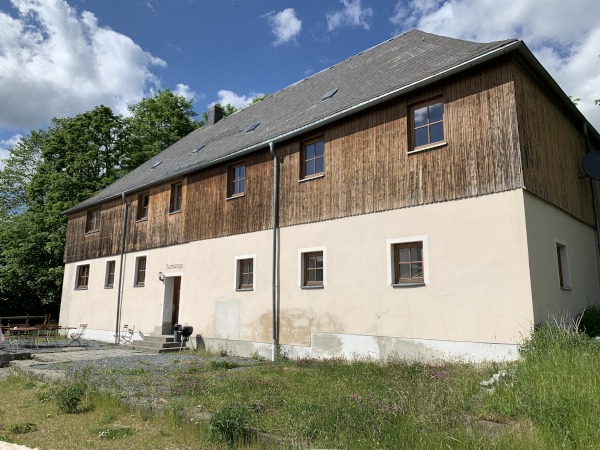 Zweigeschossiges Haus. Untergeschoss wei, Obergeschoss mit Holz verkleidet