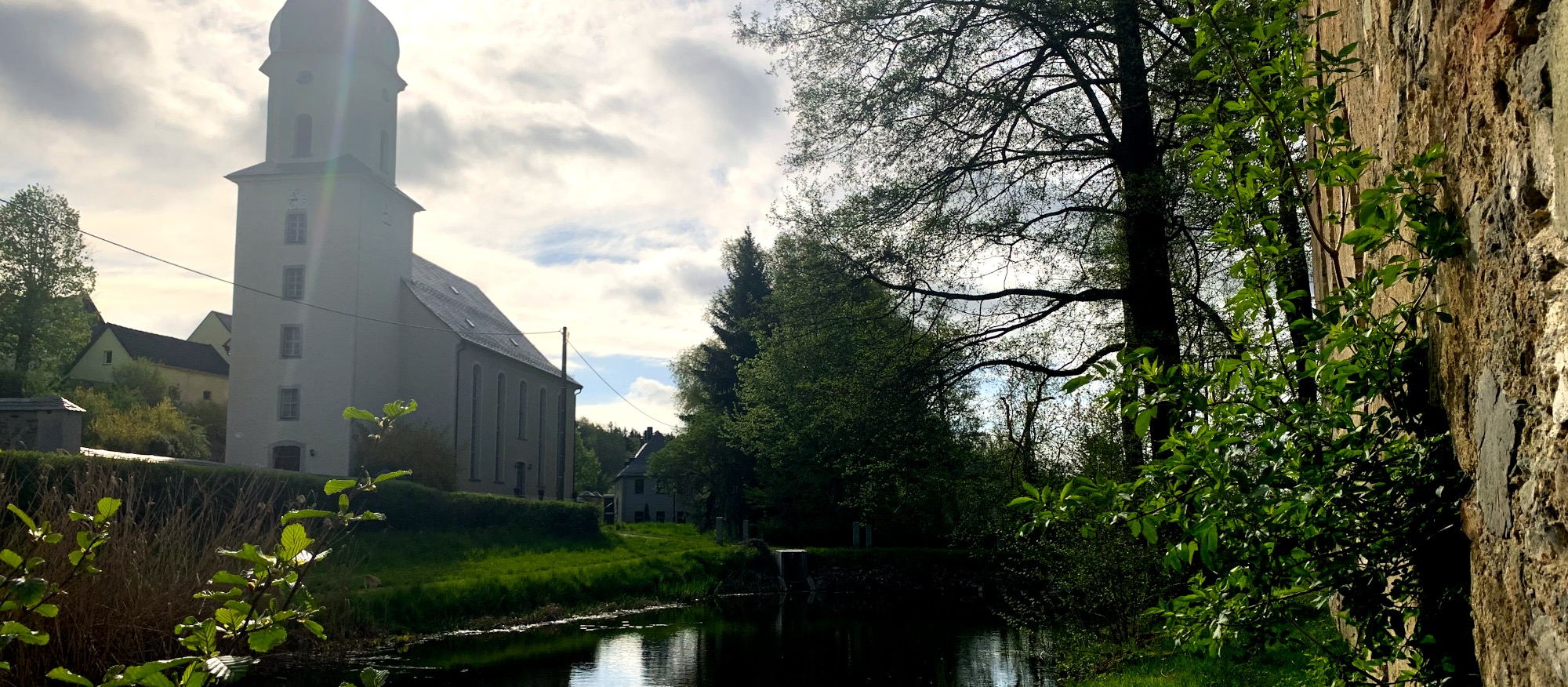 Sicht von Ruine ber den Wassergraben auf die Kirche von Geilsdorf