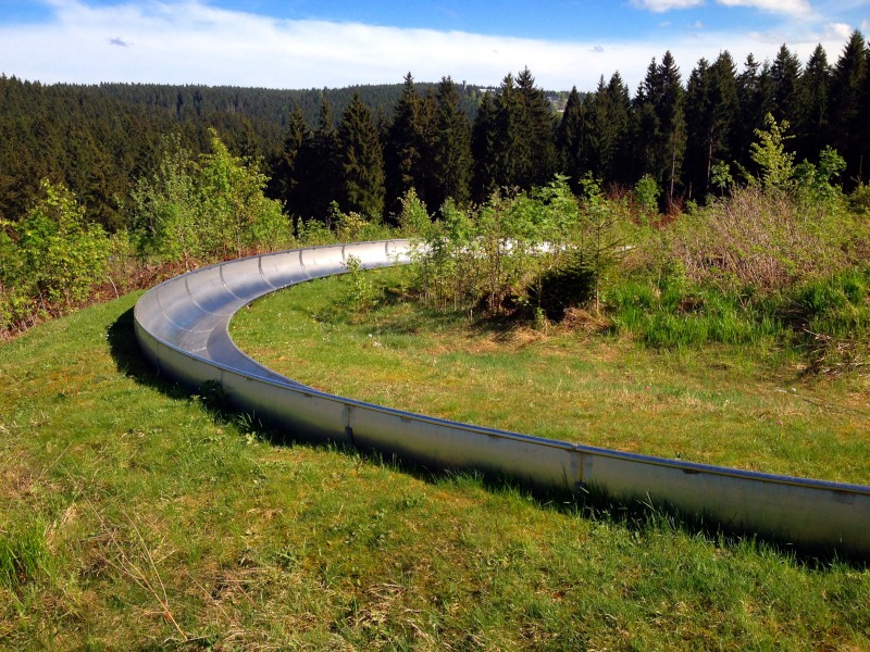 Langgezogene Rechtskurve inmitten von Wiese und Bumen auf der Sommerrodelbahn