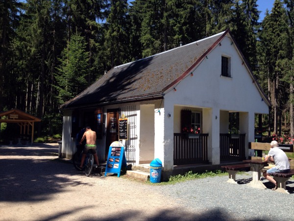 Kleines weies HAus vor Wald mit Verkaufsfenster und Angebotstafeln