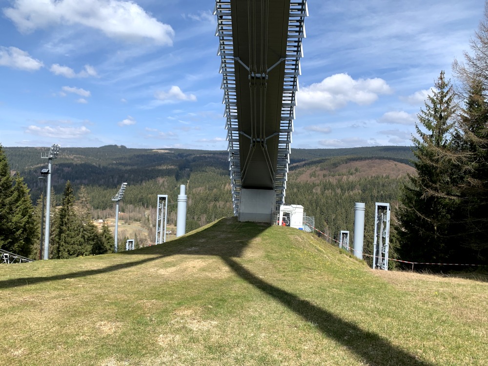 Sprungschanze von unten auf Wiese am Berg vor Abhang