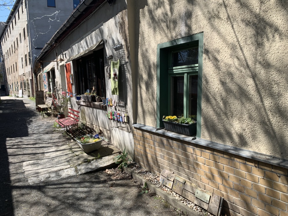 Häuserfront mit nur einem Geschoss und alter Mauer. Farbig dekoriert.